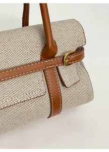 Dettaglio della trama in tela intrecciata e cinturino in pelle marrone con fibbia dorata