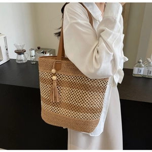 Detail of hand-woven straw shoulder bag with stylish fringe and brown leather strap