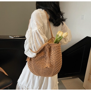 Détail d'un sac cabas tissé marron avec pompon et bandoulière épaisse en corde tressée