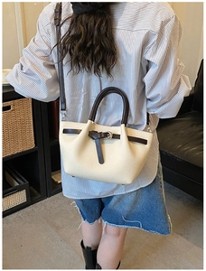 Détail d'un sac bandoulière beige et marron avec texture litchi et sangle à boucle élégante