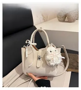 Détail du sac seau blanc cassé avec ruban, breloque en peluche et fermoir en métal
