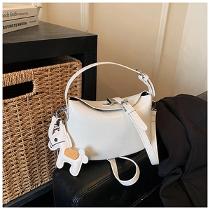White minimalist crossbody bag detail featuring a decorative horse charm and belt buckle