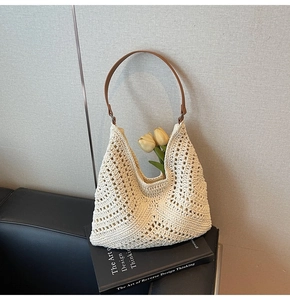 Detailed macro view of cream crochet knit texture and brown leather strap on tote bag