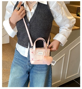 Detailed view of pink plaid mini tote bag with plush heart pendant and crossbody strap