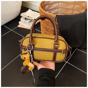 Detail der gelben Boston-Tasche mit braunem Besatz, Litschi-Leder und Taschenanhänger