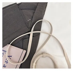 Détail du sac seau crème minimaliste avec bandoulière arrondie et poignée enveloppée de tissu