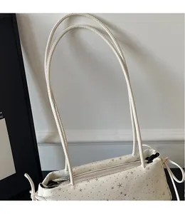 Detail of off-white baguette bag featuring grey star patterns and smooth long shoulder straps