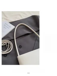 Top-down close-up of white minimalist crescent shoulder bag with two straps and silver hardware