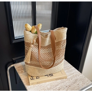 Close-up of large straw tote bag with brown straps, wood bead tassels and tulip decor