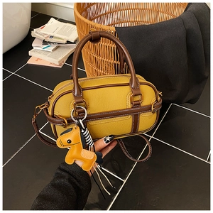 Details der gelben Boston-Tasche mit Leder-Litchi-Muster und braunen Griffen