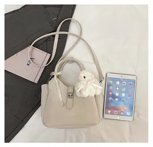 Détail du sac seau beige avec charm lapin en peluche et référence de taille avec iPad