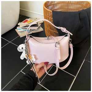 Close-up of pink pleated hobo bag with a white horse charm and adjustable strap