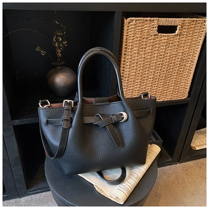 Détail du sac à main noir en cuir grainé avec sangle nouée et boucle métallique polie