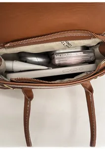 Vista interna della borsa in pelle marrone che mostra la capacità per telefono e trucchi