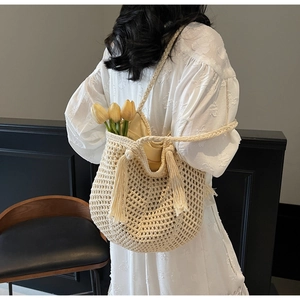 Détail du sac seau tissé beige avec glands et bandoulière pour un style de vacances