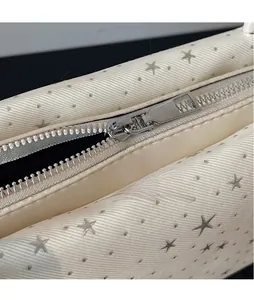Close-up of silver metal zipper and star-printed pattern on cream baguette bag