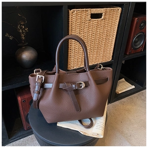 Sac à main marron en cuir grainé avec boucle métallique sur un plateau décoratif vintage