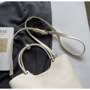 Vue détaillée du sac seau crème montrant la bandoulière réglable et la texture du cuir