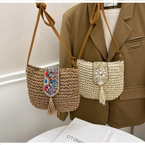 Detail of bohemian straw shoulder bags featuring ethnic embroidery and long fringe tassels