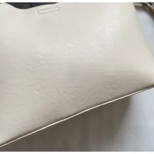 Gros plan sur un sac seau en cuir blanc montrant la texture grainée et les coutures fines