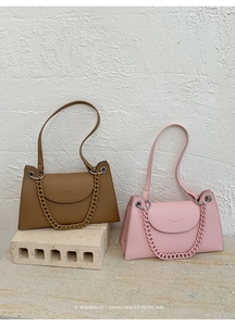 Close-up of lychee grain leather texture and metallic chain detail on fashion handbags