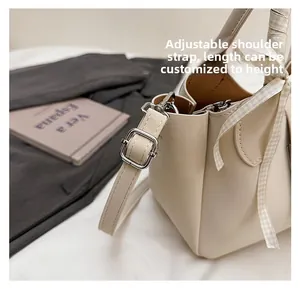 Détail de la bandoulière en cuir réglable avec boucle en métal argenté sur un sac seau beige