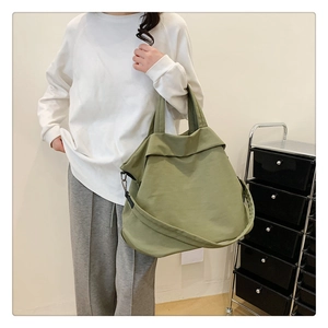 Détail d'un grand sac cabas en nylon vert porté par un mannequin pour un look décontracté