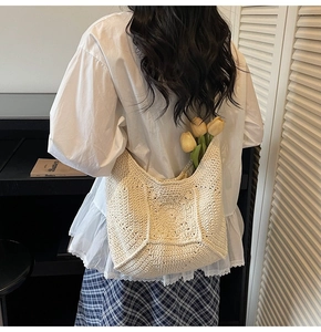 Détail d'un sac seau en maille crochet crème avec motifs floraux et textures ajourées