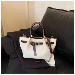 Détail du sac rétro en cuir grainé crème avec poignées brunes et boucle décorative