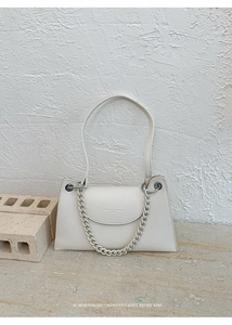 Detail of minimalist cream trapezoid bag with lychee texture and matte chain handle