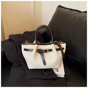 Gros plan d'un mini sac à main en cuir crème avec des poignées marron foncé