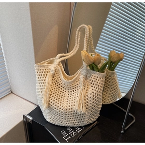 Détail d'un sac cabas au crochet beige avec motif résille, pompons et tulipes