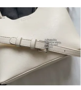 Détail de la bandoulière réglable en cuir avec boucle argentée sur un sac seau blanc