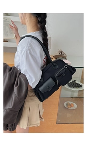 Functional black multi-pocket shoulder bag with metal zippers and buckles worn by model
