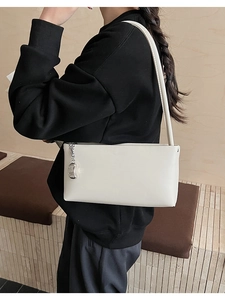 Detail of white PU leather shoulder bag with silver bean pendant and metal chain