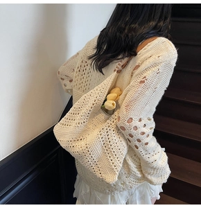 Close-up of cream crochet knit tote bag with brown leather strap and floral details