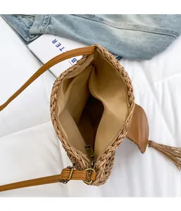 Detail view showing top zipper closure and inner lining of khaki woven straw shoulder bag