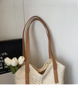 Detail of woven beach tote with reinforced X-stitching and long brown leather handles
