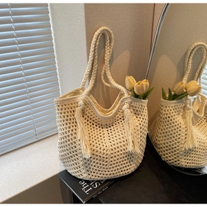 Détail du sac cabas tissé crème avec texture filet, pompons et poignées torsadées