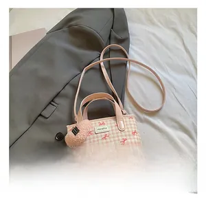 Detail of pink plaid bucket bag with bow print and soft heart keychain pendant
