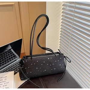 Detail of black canvas baguette bag with white star patterns and long leather shoulder straps
