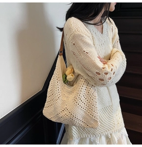 Detailed close-up of beige crochet tote bag with brown leather strap and hollow knit texture