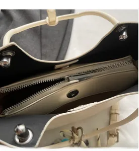 Vue détaillée de l'intérieur du sac seau beige avec poche zippée et fermoir magnétique