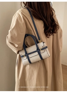 Dettaglio di una borsa a tracolla color-block minimalista su una modella in trench kaki