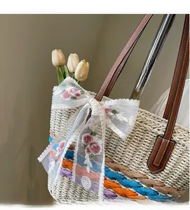 Detail of hand-woven straw tote bag with colorful stripes and floral lace bow decoration