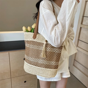 Large woven straw tote bag with brown leather straps and tassels for beach vacations