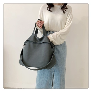 Sac bandoulière en nylon gris foncé porté par un modèle pour un style minimaliste