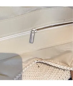 Close-up of the smooth metal zipper and inner lining on the beige woven beach tote bag