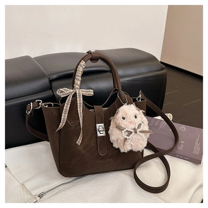 Détail du sac seau marron café avec foulard en soie à carreaux et breloque lapin rose