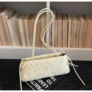 Detail of cream baguette bag featuring silver star patterns and decorative drawstrings